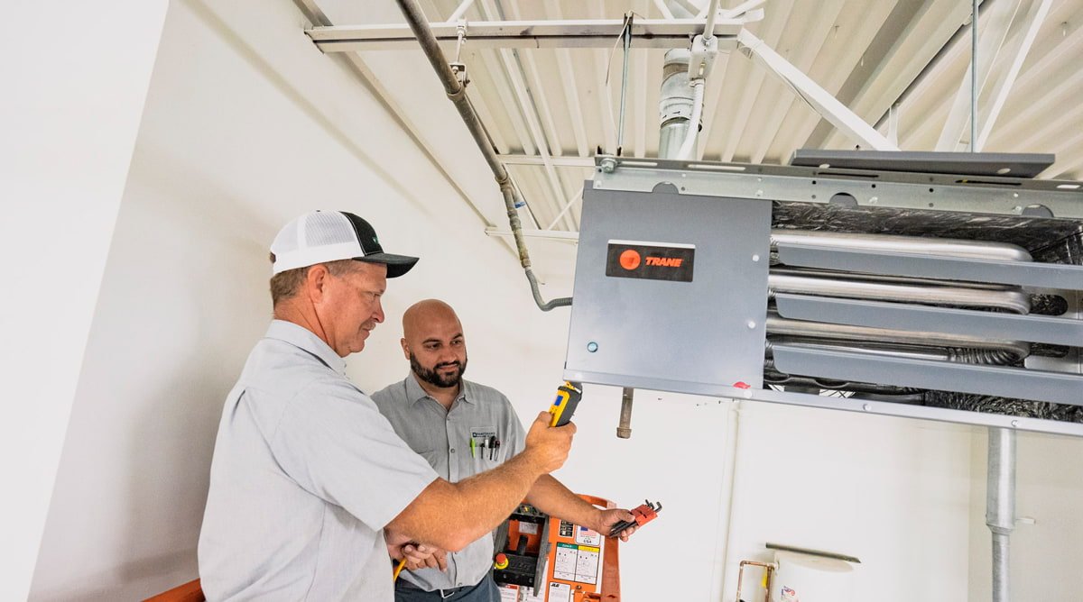 Senior technician supervising a beginner in hvac apprentice jobs training.
